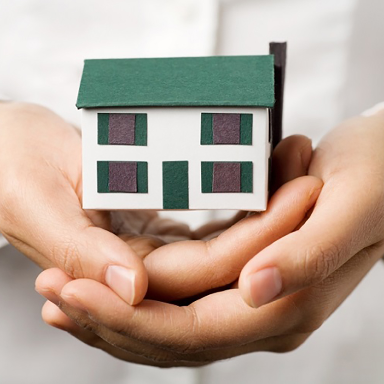 A pair of hands holding a small house. Real estate or insurance concept.